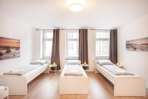 a room with three beds and two windows at TM Studio in Dortmund