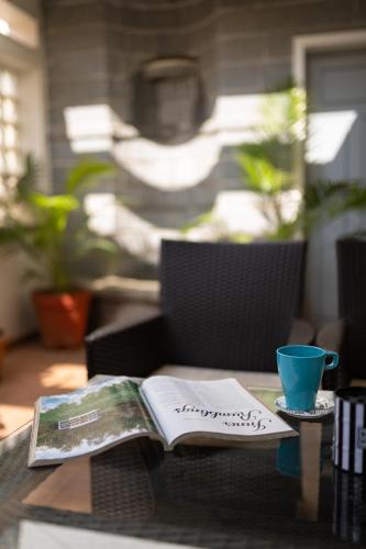 a newspaper and a cup on a table with a book at Luho 187 in Bengaluru