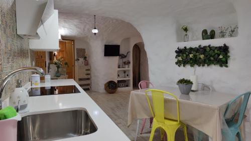 巴薩的住宿－Cueva OTTO Privada，厨房配有水槽和一张带黄椅的桌子