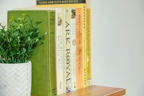 una fila di libri su uno scaffale con una pianta in vaso di 2 Bed New York Style Loft Apartment Free Parking a Bradford