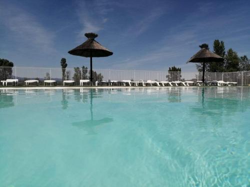 une grande piscine avec des parasols et des chaises dans l'établissement Domaine des Garrigues, à Grospierres