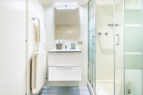 uma casa de banho branca com um chuveiro e um lavatório. em BePlace Apartments in Porta Garibaldi em Milão