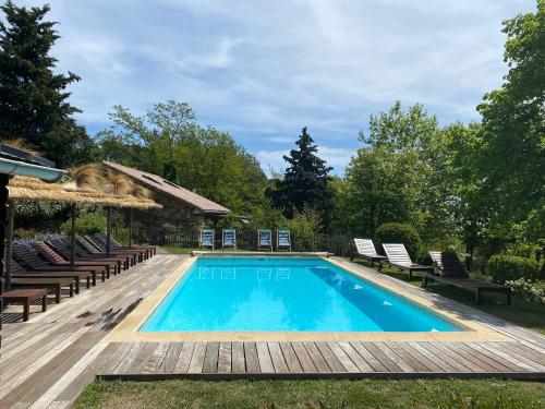 a swimming pool with chairs and a wooden deck at GITE LES GRANDES VIGNES, SUD Ardèche, indépendant et privatisé, piscine chauffée, climatisation, SPA, 11 chambres, 8 salles de bains in Sanilhac