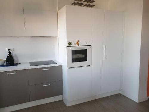a kitchen with white cabinets and a stove top oven at Condominio Schiusa in Grado