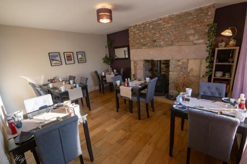 a restaurant with tables and chairs and a fireplace at Wyndgrove House in Seahouses