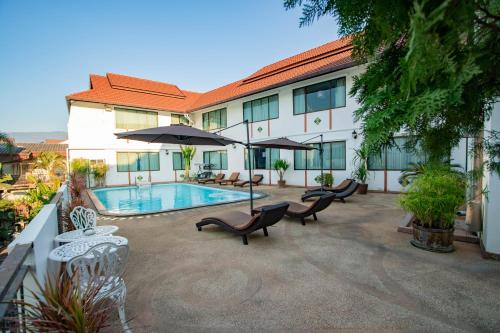 ein Hotel mit einem Pool, Stühlen und einem Sonnenschirm in der Unterkunft Eurana Boutique Hotel in Chiang Mai