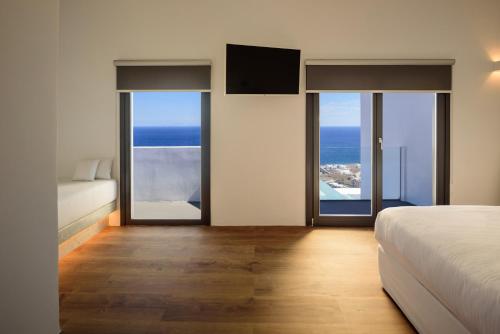 a bedroom with a bed and views of the ocean at LF Suites & Villas in Imerovigli
