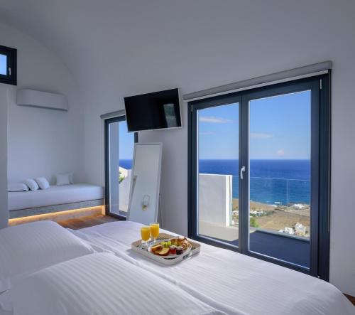 una habitación de hotel con un plato de comida en una cama en LF Suites & Villas en Imerovigli