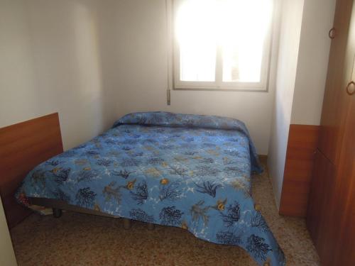 een slaapkamer met een bed met een blauw dekbed en een raam bij Flat in a great location for 8 guests - Beahost in Bibione