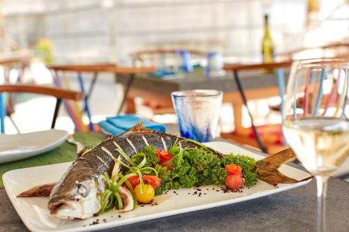 a plate of fish and vegetables on a table with a glass at Sun Siyam Iru Veli - 24 Hours Premium All-Inclusive with Free Transfers in Dhaalu Atoll