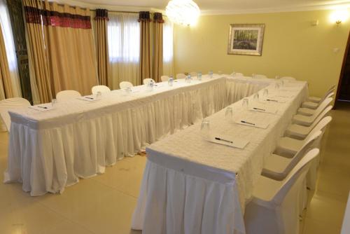 a row of tables with white chairs in a room at Royal Victoria House Ltd in Kampala