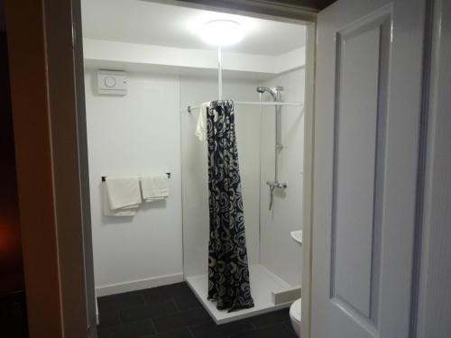 La salle de bains est pourvue d'une douche avec rideau de douche noir et blanc. dans l'établissement St. Cyrus Village Inn, à Saint Cyrus