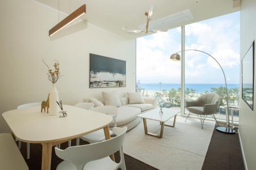 a living room with a white couch and a table and chairs at UH SUITE THE HAEUNDAE in Busan