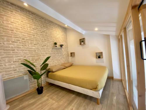 a bedroom with a yellow bed and a brick wall at Bel appartement à deux minutes de la plage in Courseulles-sur-Mer
