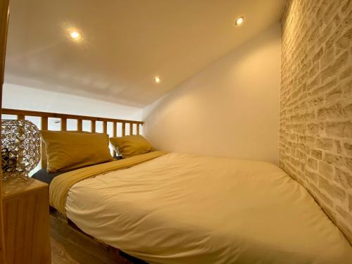 1 dormitorio con 1 cama con pared de ladrillo en Bel appartement à deux minutes de la plage, en Courseulles-sur-Mer