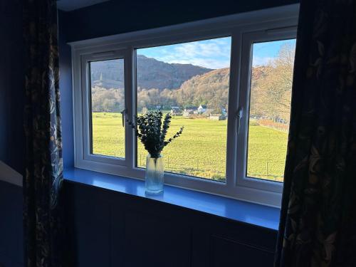 a window with a vase of flowers on a window sill at Bridge House Hotel & Silver Howe View Cottage in Grasmere