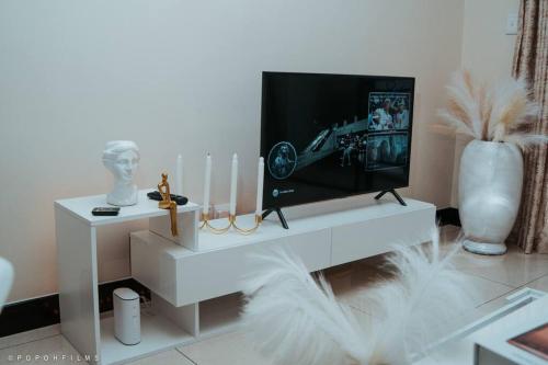 Sunset Gold-2 Bedrooms Apartment في Fourways: غرفة معيشة مع تلفزيون على طاولة بيضاء