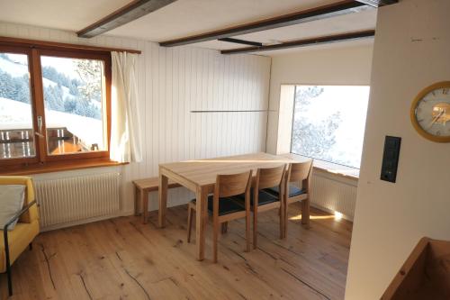 comedor con mesa, sillas y reloj en Ferienhaus Oberguet, en Unterwasser