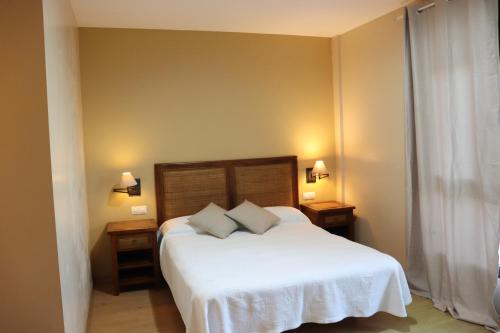 a bedroom with a white bed with two night stands at Hotel Balcón de San Bartolo in Barreiros