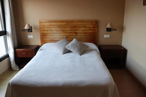 a bedroom with a large white bed with two night stands at Hotel Balcón de San Bartolo in Barreiros