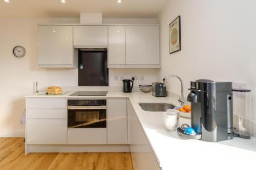 a white kitchen with a sink and a stove at Three Tuns - Garden Suite 1 in Wickham Market