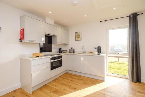 a kitchen with white cabinets and a large window at Three Tuns - Garden Suite 1 in Wickham Market