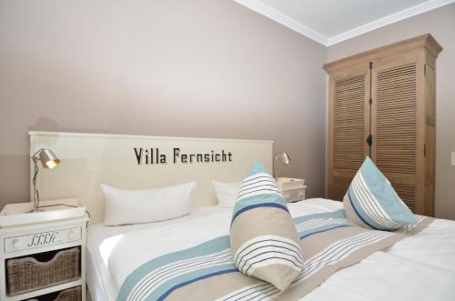 a bedroom with a white bed with blue and white pillows at Villa Fernsicht - Apt. 03 in Ostseebad Sellin