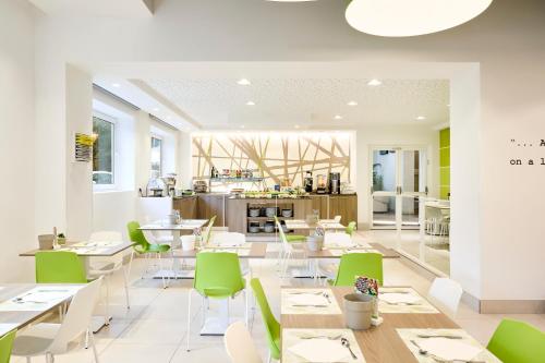 a restaurant with white tables and green chairs at Hotel Iris ***S in Lido di Jesolo