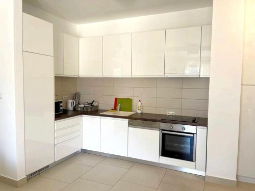 a white kitchen with white cabinets and a stove at Lavender Bay Apartment in Donji Morinj