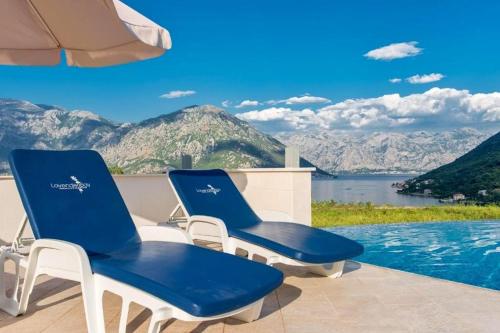 two blue and white chairs sitting next to a swimming pool at Lavender Bay Apartment in Donji Morinj