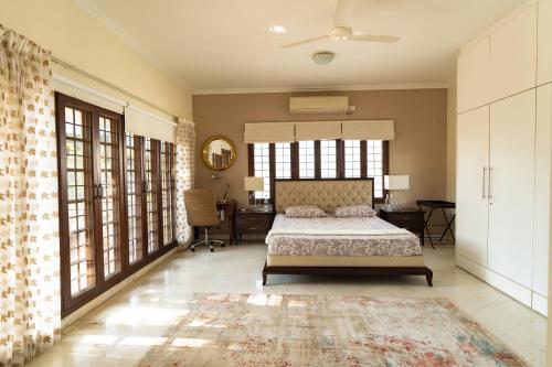 a bedroom with a bed and a desk and windows at Luho 187 in Bangalore