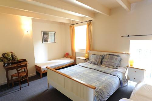 a bedroom with a bed and a window and a desk at La Goëlette in Saint-Suliac