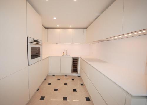 une cuisine avec des armoires blanches et un sol carrelé dans l'établissement FOCH Bright prestigious apartment in Cannes !, à Cannes