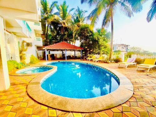 a swimming pool in front of a building with palm trees at THE TURQUOIISE HOUSE in Morjim