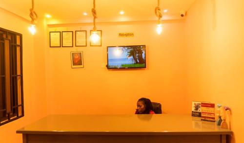 a woman sitting at a table in a room at Kiteme Comfort Lodge in Arusha