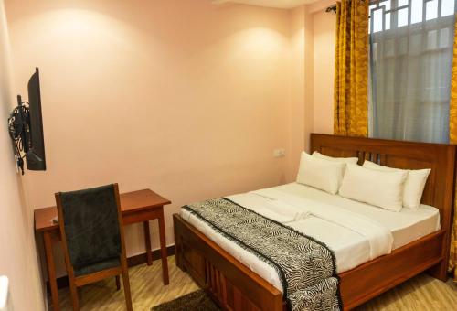a bedroom with a bed and a desk and a window at Kiteme Comfort Lodge in Arusha