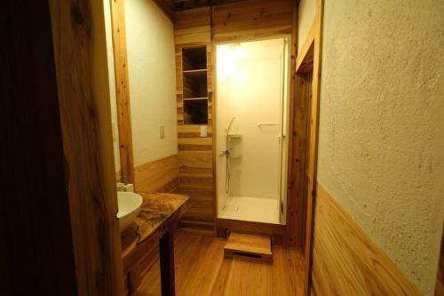 La salle de bains est pourvue d'une douche en verre et d'un lavabo. dans l'établissement スナッパーロック 屋久島, à Yakushima