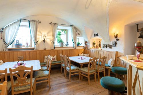 a restaurant with two tables and chairs and windows at Erlebnisgut & Reiterhof Oberhabach in Kirchdorf in Tirol