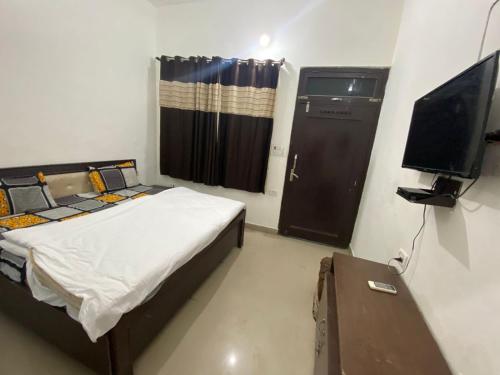 um quarto com uma cama e uma televisão de ecrã plano em Cheetal Lodge By WB Inn em Rāmnagar