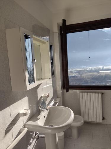 ein Bad mit einem Waschbecken, einem WC und einem Fenster in der Unterkunft Appartamento vacanza il Picchio Rosso in Mantello