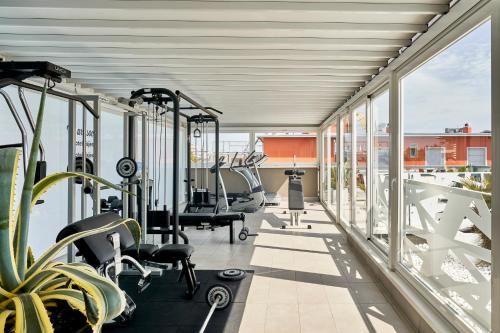 - une salle de sport avec tapis de course et vélos elliptiques dans un bâtiment dans l'établissement Hotel Iris ***S, à Lido di Jesolo