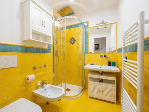 a yellow bathroom with a sink and a shower at Artist House in Positano in Positano