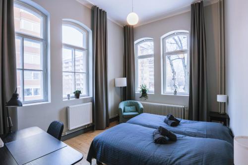 a bedroom with a blue bed and two windows at Holterman Hostel in Gothenburg