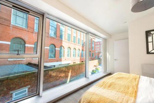 a bedroom with large windows and a bed with a blanket at Brand New Luxury 1-Bed Apartment in Liverpool in Liverpool