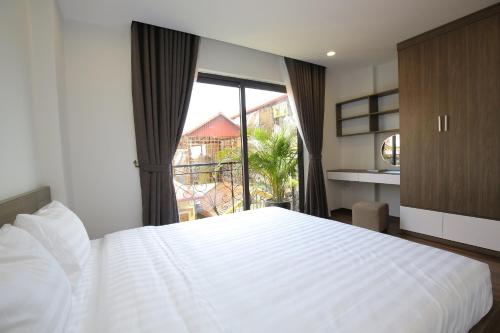 a bedroom with a white bed and a large window at Sumitomo9 Apartments & Hotel - alley 58 Dao Tan in Hanoi