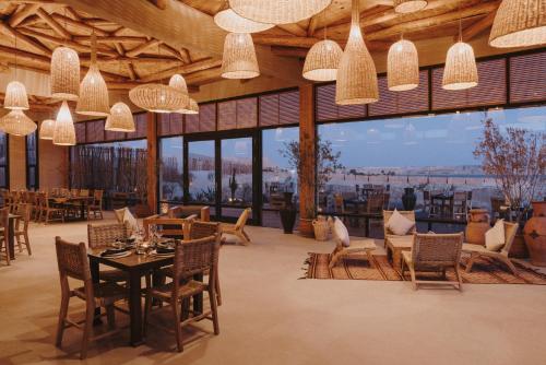 a restaurant with tables and chairs and large windows at Caravan Dakhla by Our Habitas in Dakhla