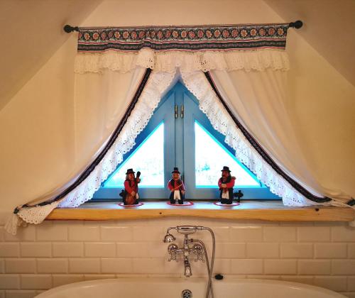 three toy figurines sitting on a window sill in a bathroom at KAAJowka Ludowa Chata w Bieszczadach in Wetlina