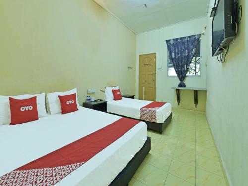 a hotel room with two beds and a television at OYO 90706 Empire Inn 2 in Kota Bharu