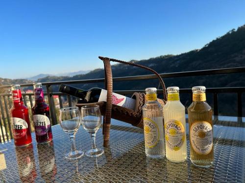 - une table avec des bouteilles de vin et des verres sur le balcon dans l'établissement Idyllic Private Cottage w/King Bed + Mountain view, à Kasauli