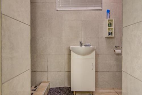 a bathroom with a white sink and a mirror at Ovendales Self Catering Cottage in Benoni